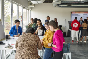 Groups of people gathered around tables while working together at a workshop.